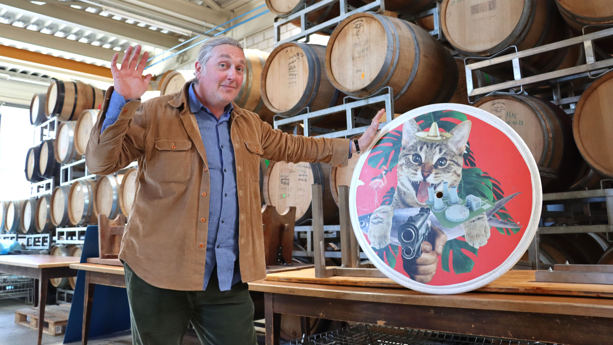 "Ne tirez pas, ou alors seulement une pression!" Devant les fûts de chêne qu’il utilise pour ses bières d’exception, Jérôme Rebetez s’amuse de la menace de la mascotte du chais, un chat, stylisé par son cousin Augustin Rebetez - photo EA