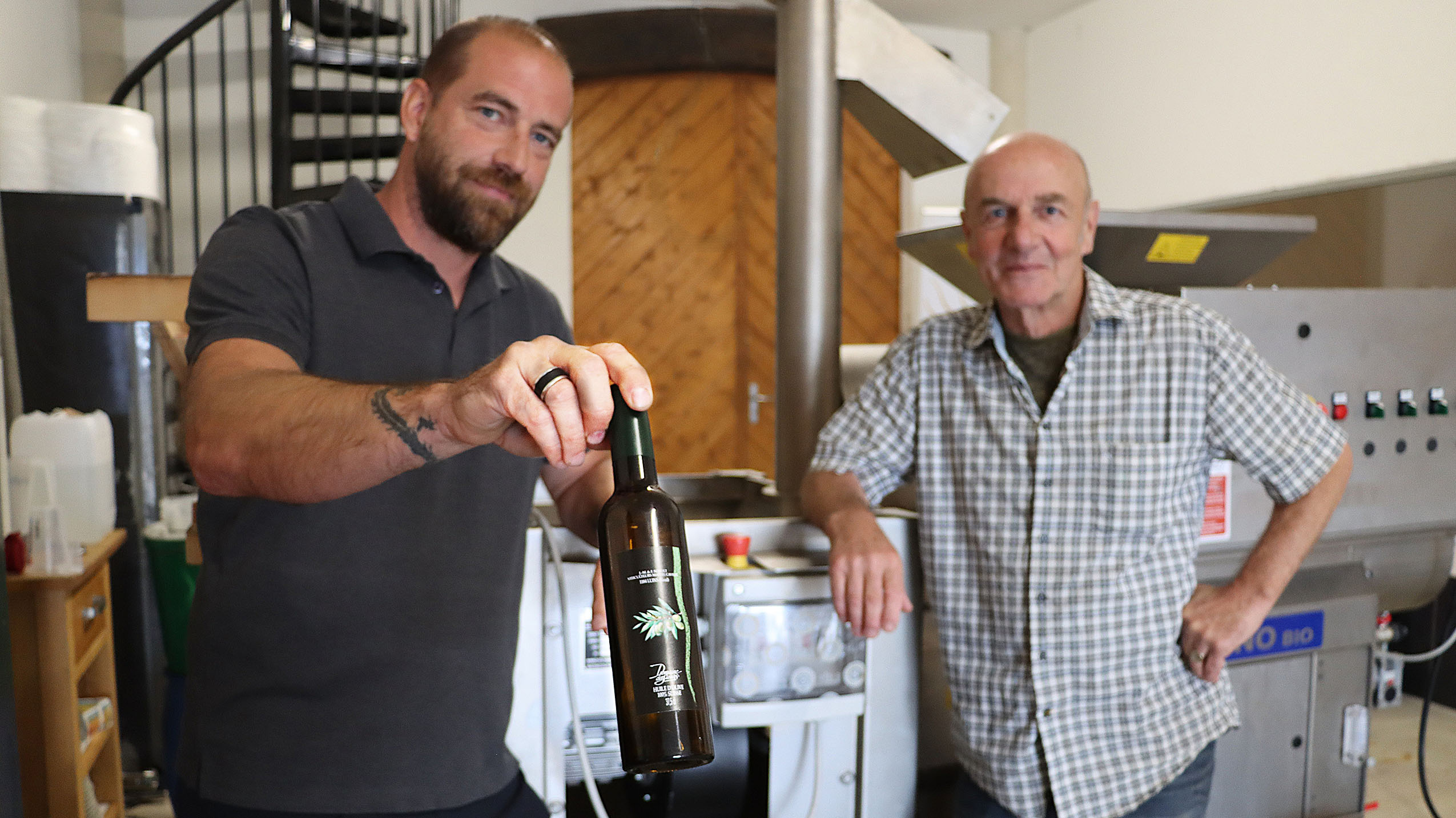 Leur star, ce sera l’huile d’olive! L’un des prototypes de bouteilles romandes nous est ici tendu par Fabien Sordet, vigneron à Luins (VD), au côté de Frank Siffert (à droite), premier président de la toute fraîche association – photo EA